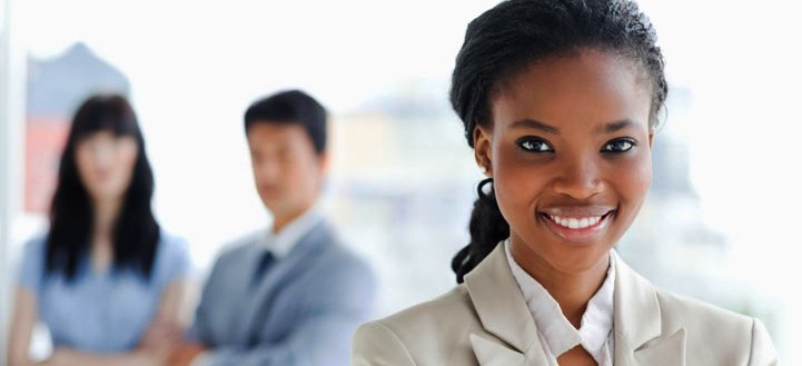 Young smiling businesswoman with team behind her